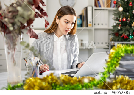 Businesswoman doing her daily work in office during Christmastime Businesswoman doing her daily work in office during Christmastime 96052307