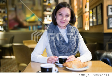Smiling brunette sitting in empty cafe with cup of coffee 96052743
