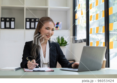 Charming asian businesswoman sitting working on laptop in office. Charming asian businesswoman sitting working on laptop in office. 96053424
