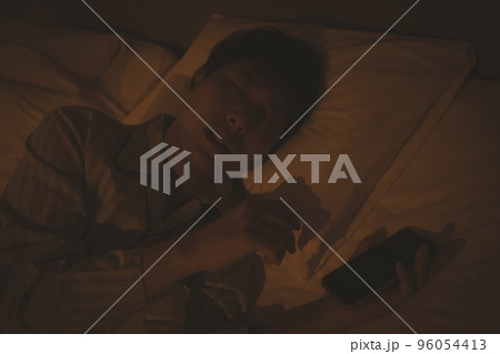 寝室とスマホを持ったまま寝る40代男性 96054413