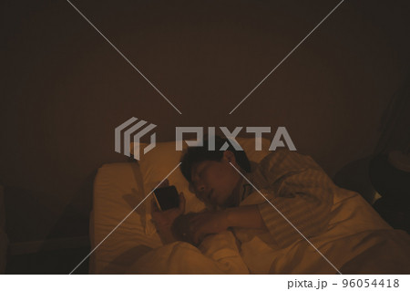 寝室とスマホを持ったまま寝る40代男性 寝室とスマホを持ったまま寝る40代男性 96054418