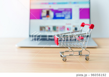 Shopping cart and laptop computer with marketplace website. business, technology, ecommerce, digital banking and online payment concept Shopping cart and laptop computer with marketplace website. business, technology, ecommerce, digital banking and online payment concept 96056192