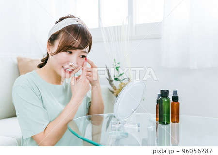 家で笑顔で鏡を見る女性（目・コンタクトレンズ） 96056287