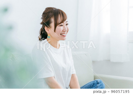 家でリラックスしてソファでくつろぎながら幸せを感じる笑顔の日本人女性の横顔 96057195