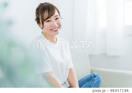 家でリラックスしてソファでくつろぎながらカメラ目線で笑顔の日本人女性の横顔 96057196