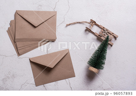 Empty craft envelopes, a Christmas tree and a wooden sledge on plaster. Top view. 96057893