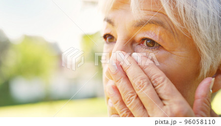 She gets teary when she misses her loved one. Closeup shot of a sad senior woman wiping tears off her face outdoors. 96058110