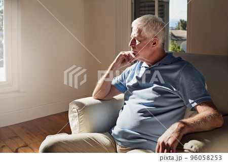 Lost in memories. Shot of a pensive senior man sitting in a chair at home alone. Lost in memories. Shot of a pensive senior man sitting in a chair at home alone. 96058253