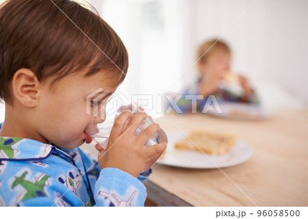 Washing it down. A cute little boy having a drink of water with breakfast. 96058500