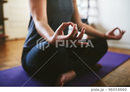 Finding my balance. Cropped shot of an unrecognizable woman sitting on a yoga mat and meditating alone in her home. Finding my balance. Cropped shot of an unrecognizable woman sitting on a yoga mat and meditating alone in her home. 96058660