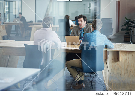 Getting straight to the point. Through the glass shot of a group of colleagues working together in an office. Getting straight to the point. Through the glass shot of a group of colleagues working together in an office. 96058733