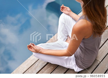 Calmness of the still waters. Cropped closeup of a young woman meditating poolside. 96058955