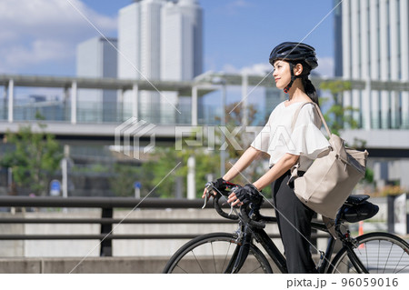 バックパックを肩にかけて、ロードバイクを引いて歩くビジネスウーマン　横から 96059016