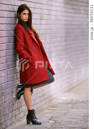 Winter ready in red. Portrait of a gorgeous young woman leaning against a brick wall in the city. 96059533