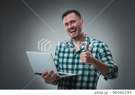 Portrait of young handsome man using laptop, wearing plaid shirt 96060294