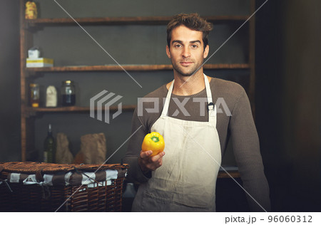 Hes a pro in the kitchen. Shot of a young man holding a yellow pepper in his kitchen. 96060312