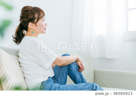 家でリラックスしてソファでくつろぎながら座る笑顔の日本人女性の横顔 96060923