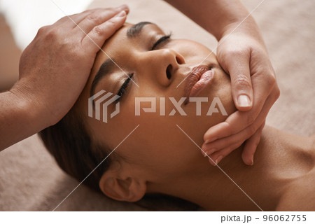 Massaging the body and mind. Shot of a beautiful young woman getting a head massage at a spa. 96062755