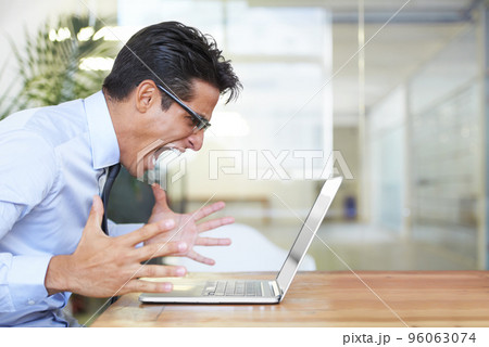 When your computer crashes. Profile of an angry businessman shouting at his laptop at work. 96063074