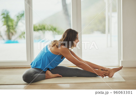Its all about the warmup. Full length shot of a young woman practicing yoga at home. Its all about the warmup. Full length shot of a young woman practicing yoga at home. 96063301