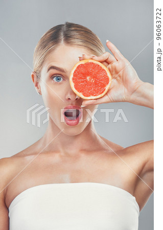 Wow studio portrait, woman with grapefruit for skincare wellness, beauty and face health by grey wall. Cosmetics model, surprise girl with fruit for healthy facial skin or vitamin c by background Wow studio portrait, woman with grapefruit for skincare wellness, beauty and face health by grey wall. Cosmetics model, surprise girl with fruit for healthy facial skin or vitamin c by background 96063722