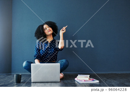 Act on your dreams. Studio shot of an attractive young woman looking thoughtful while using a laptop against a blue background. Act on your dreams. Studio shot of an attractive young woman looking thoughtful while using a laptop against a blue background. 96064228