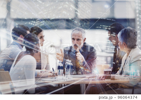 Serious strategizing into the evening. Multiple exposure shot of a group of businesspeople brainstorming together superimposed on a city at night. 96064374