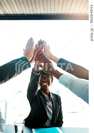 Bring it in for success. Cropped shot of a group of businesspeople high-fiving in an office. 96064644