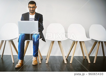 Preparing an interesting introduction before his interview. Shot of a young businessman using a laptop while waiting in line. 96065430