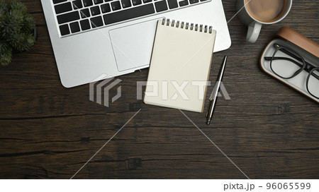 Above view of blank notepad, laptop, glasses and coffee cup and wooden working desk 96065599
