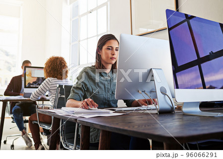 Technology ensures their workday is a productive one. Shot of colleagues working on their computers in an open plan office. 96066291