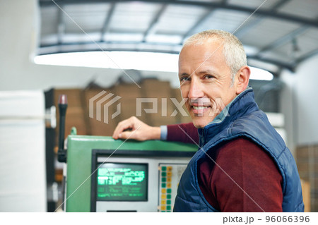This panel is the nerve center of the factory. Portrait of a mature man standing next to machinery in a factory. 96066396