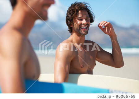 Excited for some surfing. Two friends making their way to the ocean, joking along the way. 96066769