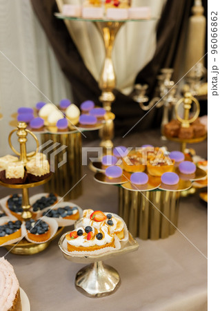 Table with cakes, sweets, candy, buffet. Dessert table for a party goodies for the wedding banquet area. Close up candy bar. Decorated delicious. 96066862