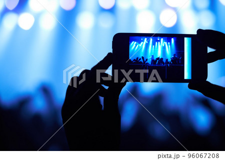 Cropped shot of a person filming their favorite band with a camera phone. This concert was created for the sole purpose of this photo shoot, featuring 300 models and 3 live bands. All people in this Cropped shot of a person filming their favorite band with a camera phone. This concert was created for the sole purpose of this photo shoot, featuring 300 models and 3 live bands. All people in this 96067208