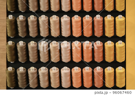 Row of multi-colored thread spools in brown orange yellow tones 96067460
