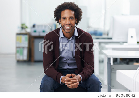 He knows its important to enjoy his work. Shot of a young businessman sitting in an office. 96068042
