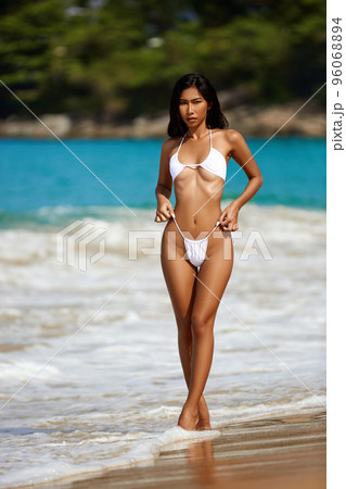 Beautiful asian girl in white bikini posing at the tropical beach 96068894