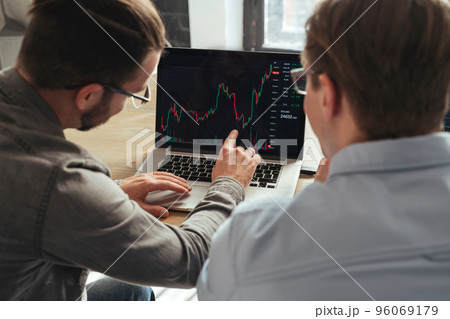 Over shoulder view of trader couch teaching another man basics of cryptocurrency investments Over shoulder view of trader couch teaching another man basics of cryptocurrency investments 96069179