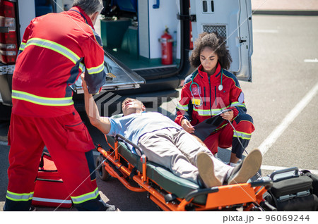 Paramedical workers providing emergency medical care to an accident victim 96069244