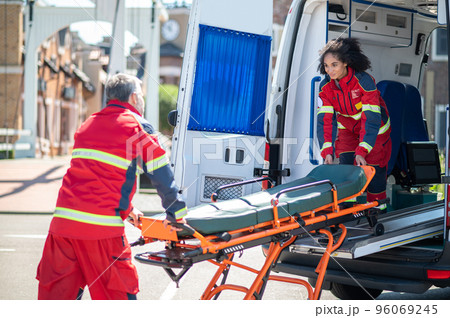 Paramedical workers taking a stretcher out of the EMS vehicle 96069245