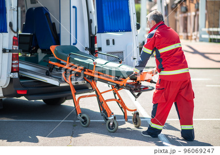 Paramedic taking the gurney out of the ambulance van 96069247