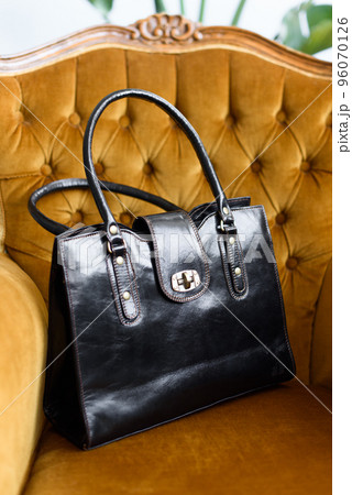 close-up photo of orange leather bag on a yellow velor vintage armchair. 96070126