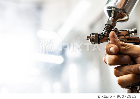 Paint spray gun in the hands of a painter close up Paint spray gun in the hands of a painter close up 96072915