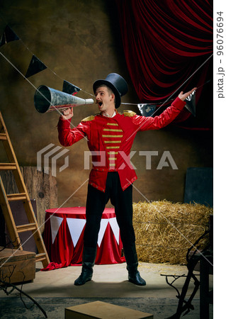 Vintage portrait of male retro circus entertainer expresses rejoice and announces start of show over dark retro circus backstage background. Vintage portrait of male retro circus entertainer expresses rejoice and announces start of show over dark retro circus backstage background. 96076694