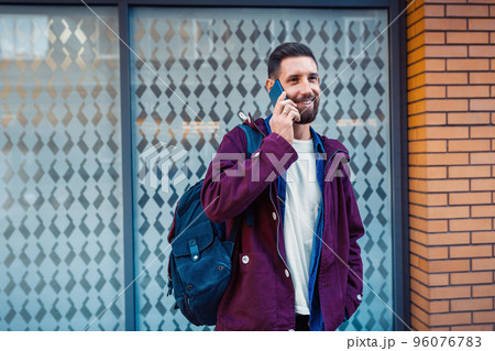 Half length portrait of handsome bearded man dressed in fashionable clothes standing on street. 96076783
