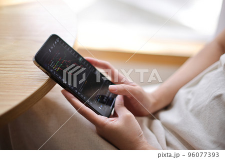 Woman hand using a smartphone for Stock exchange trading online in the coffee shop, business concept 96077393