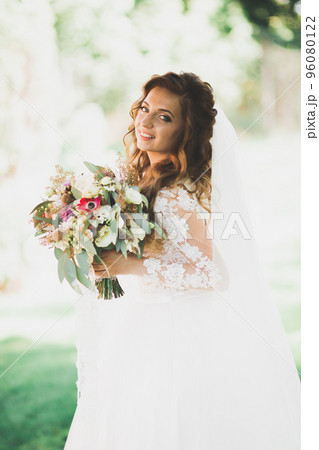 Beautiful bride posing in wedding dress outdoors Beautiful bride posing in wedding dress outdoors 96080122