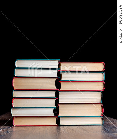 Two stacks of hardback books against a dark background. 96082136