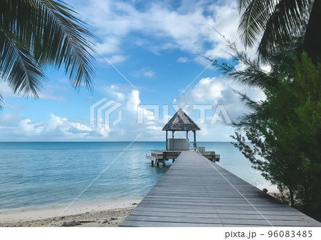 Wooden gazebo on lonley tropical beach pier. Exotic island with coconut palm tree branch and sand shore. Summer landscape, vacation, holidays, travel concept. Summer background. Wooden gazebo on lonley tropical beach pier. Exotic island with coconut palm tree branch and sand shore. Summer landscape, vacation, holidays, travel concept. Summer background. 96083485